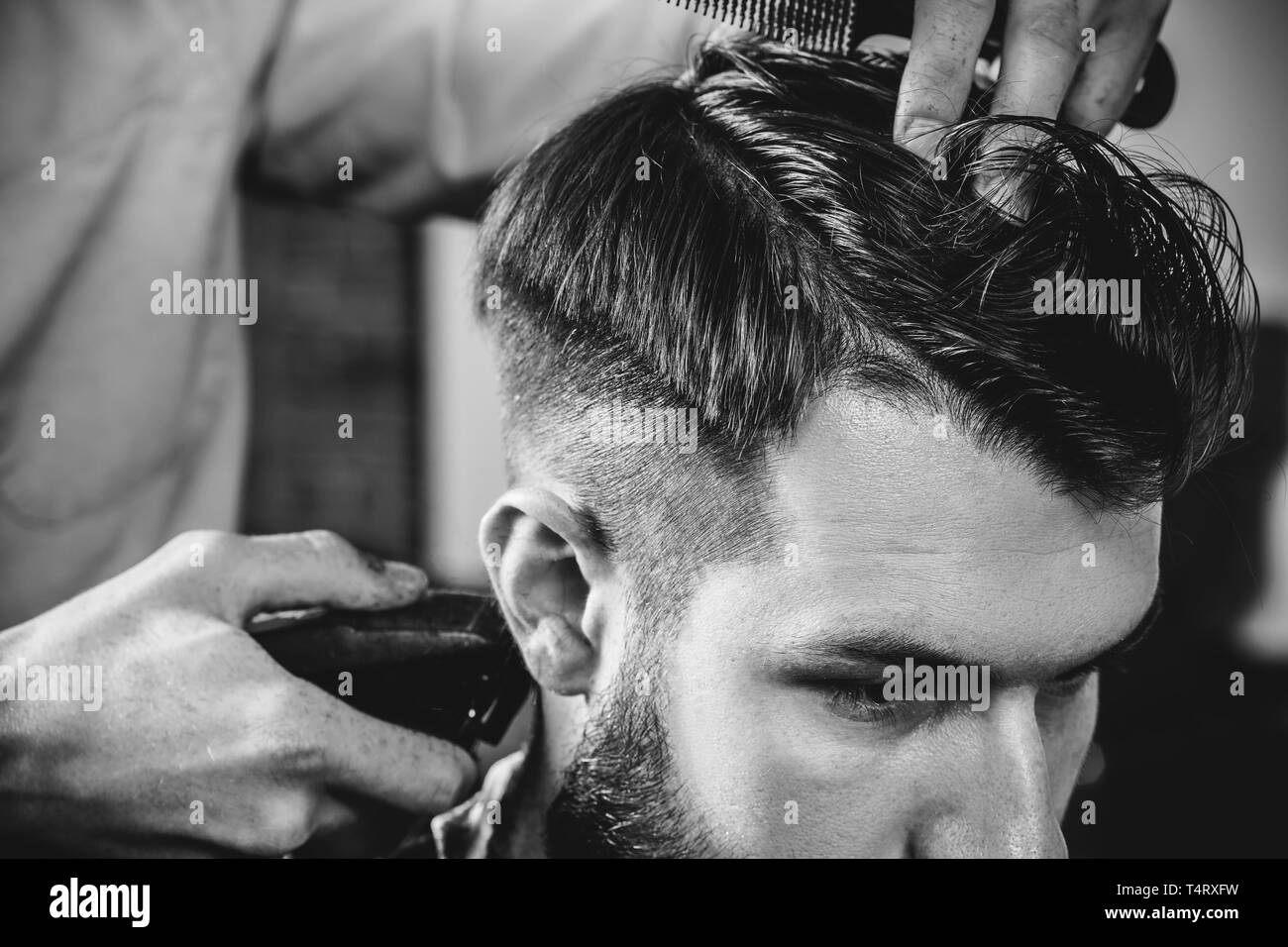Young handsome barber making haircut for attractive bearded man at  barbershop. Black and white or colorless photo. Hairstyle, salon,  hairdresser, barber shop, lifestyle concept. Caucasian male models Stock  Photo - Alamy