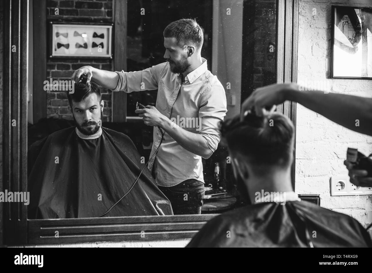 Young handsome barber making haircut for attractive bearded man at  barbershop. Black and white or colorless photo. Hairstyle, salon,  hairdresser, barber shop, lifestyle concept. Caucasian male models Stock  Photo - Alamy