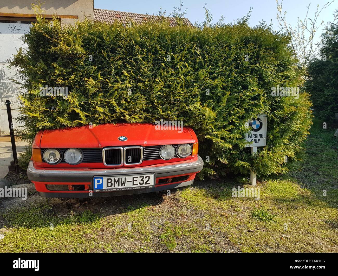 Ostritz, Saxony/Germany - April 6th 2019. Special private parking lot reserved for BMW cars only. Funny because of old BMW E32 stuck in a hedge Stock Photo