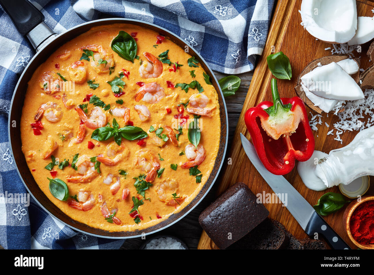 Shrimps in Coconut Sauce with blended vegetables in a skillet on a rustic wooden table with ingredients, camarao no leite de coco, brazilian recipe, v Stock Photo