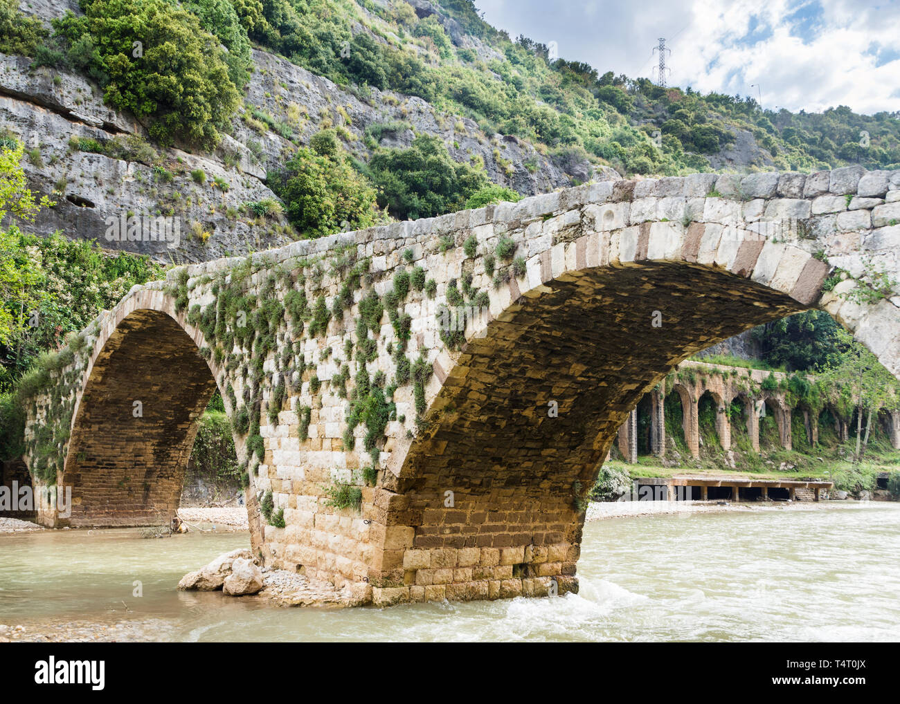 The old Mamluk stone bridge and the 17-arches Roman aqueduct in Nahr el Kalb, Lebanon Stock Photo