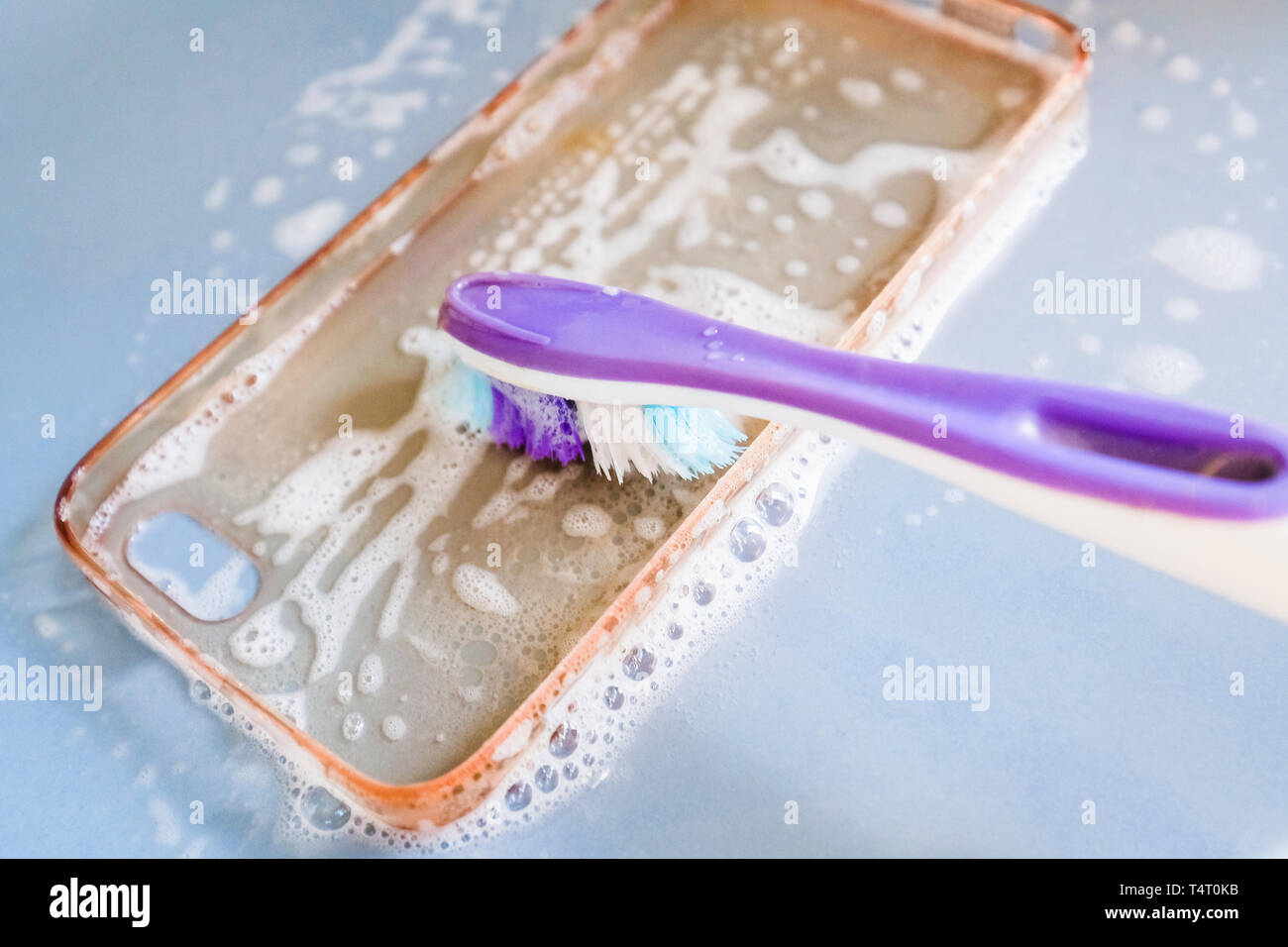 Cleaning the silicone phone case with toothbrush, foam and soap