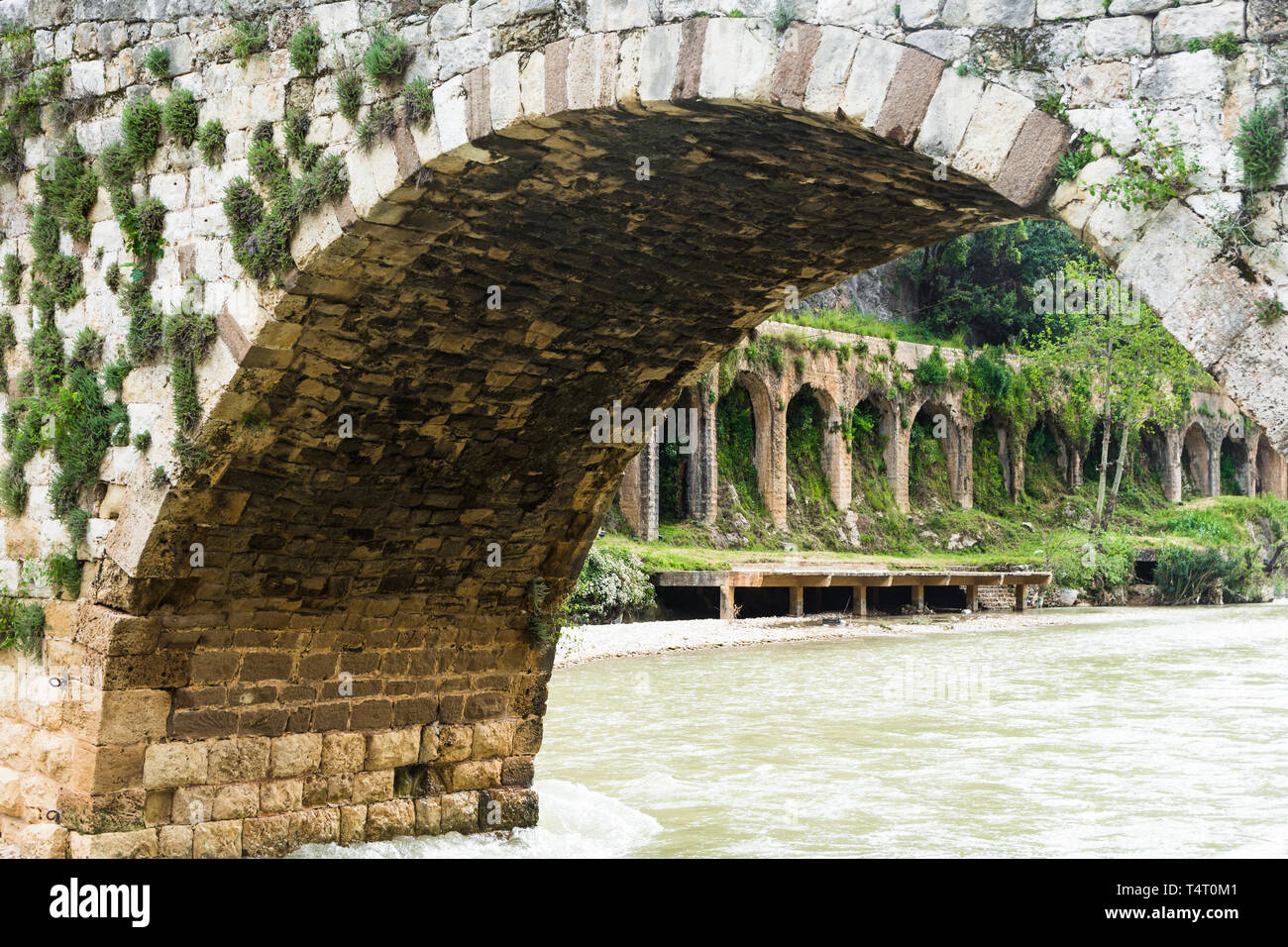 The old Mamluk stone bridge and the 17-arches Roman aqueduct in Nahr el Kalb, Lebanon Stock Photo