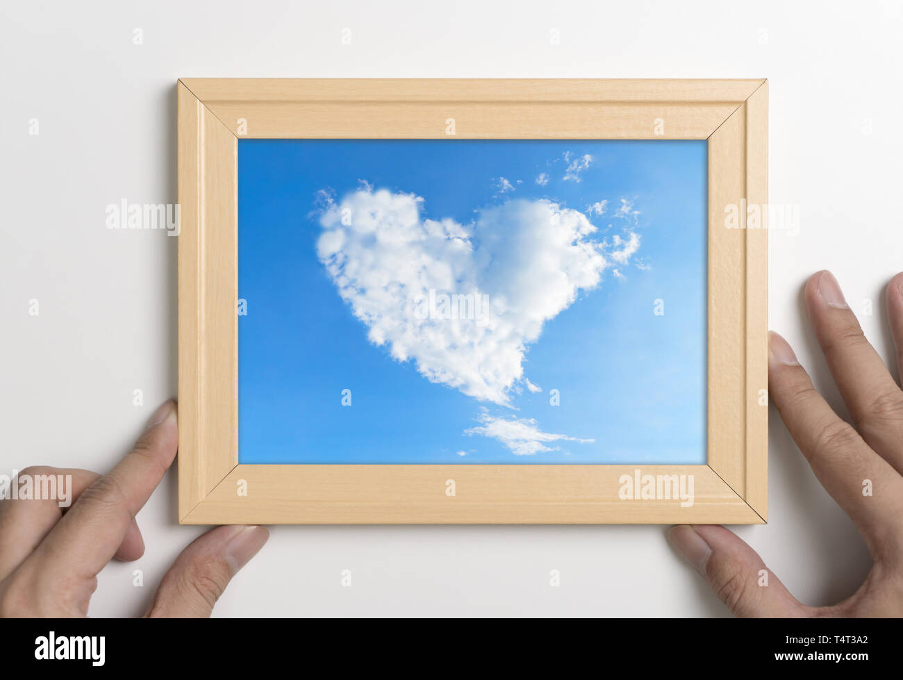 Hands holding picture frame with cloud heart Stock Photo