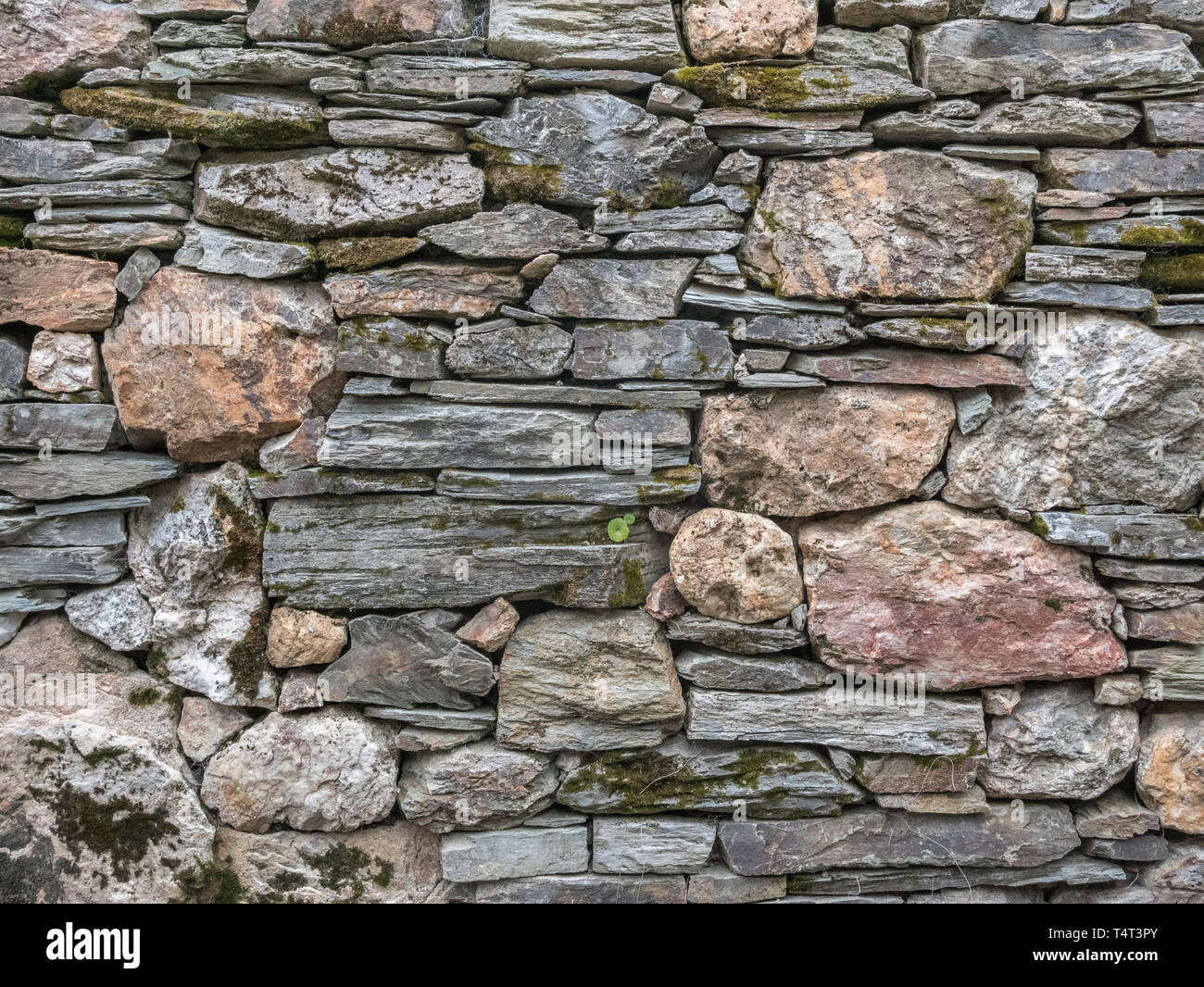 Randomly / ramshackle laid stone wall. Metaphor haphazard, uneven, irregular, variable, irregular stonework. Stock Photo