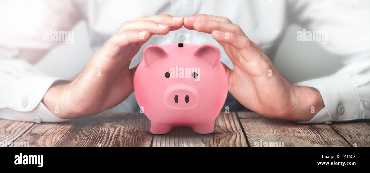 Protecting Hands Over Pink Piggy Bank - Financial Security Concept Stock Photo