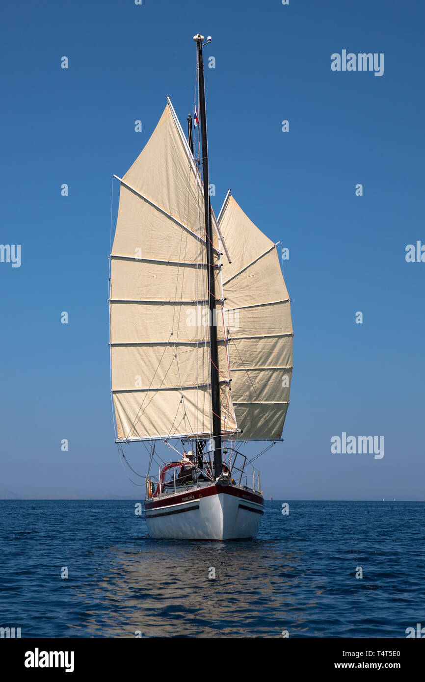 'Freelance', a Freedom 30 junk-rigged ketch, sailing downwind in the Murtersko more (Murter Sea), Adriatic, Šibenik-Knin, Croatia.  MODEL RELEASED Stock Photo