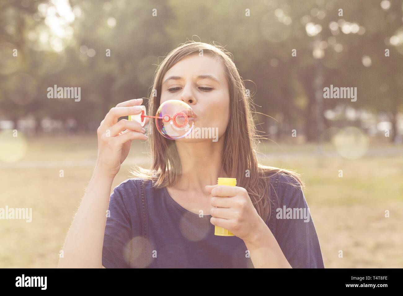 Young woman making soap bubbles, Germany Stock Photo