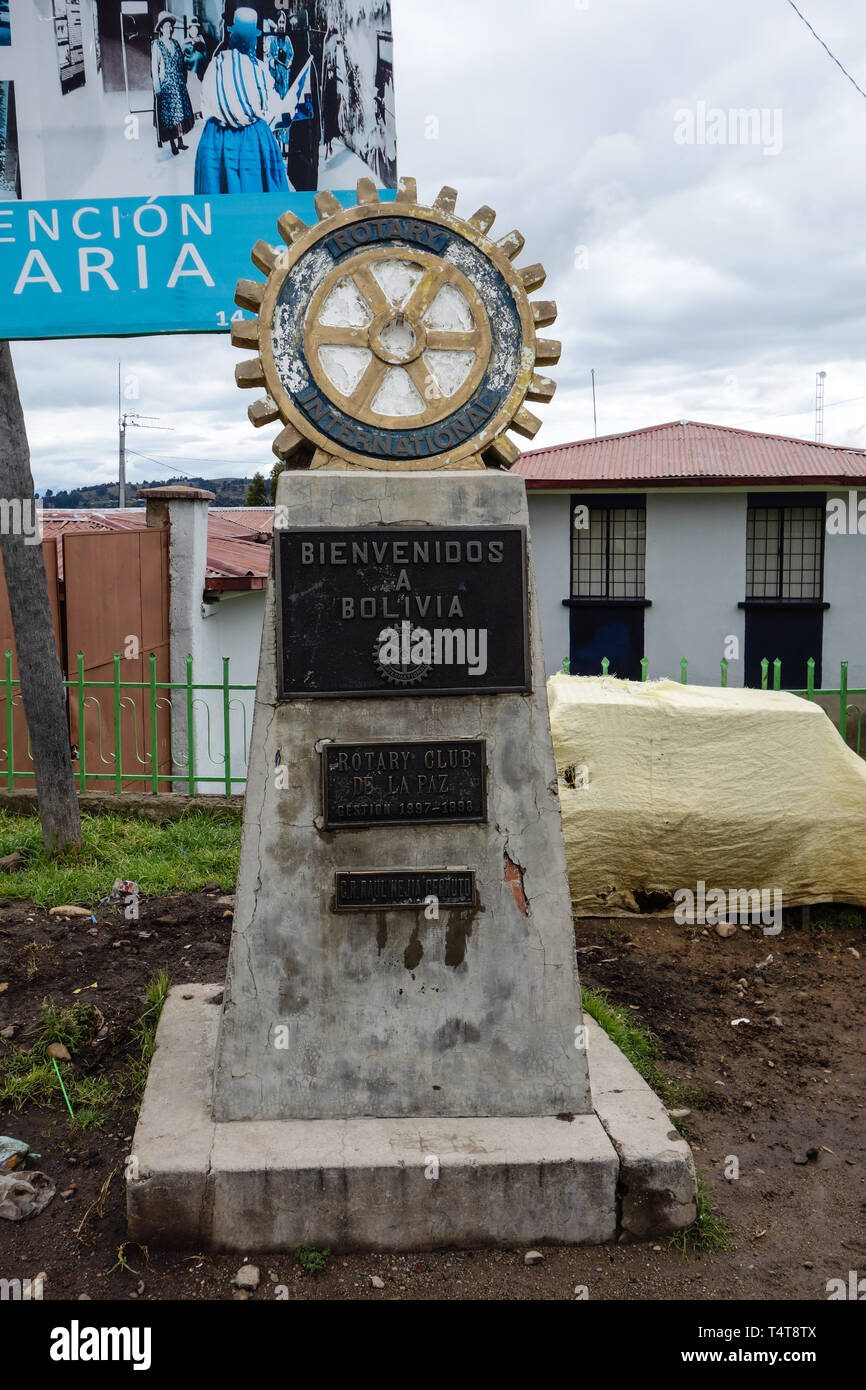 Kasani, Bolivia - 28. May 2017: Border between Bolivia and Peru, grey border stone with signs and a golden-blue gearwheel on top Stock Photo