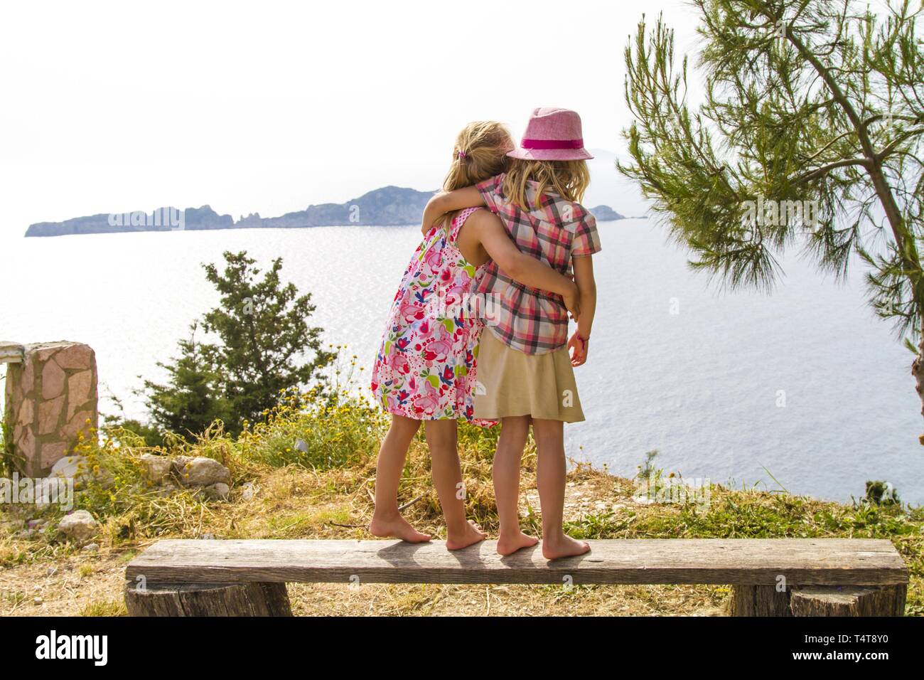 Infants (5-6) on a bench, coast at Agios Georgios, Corfu, Greece, Europe Stock Photo