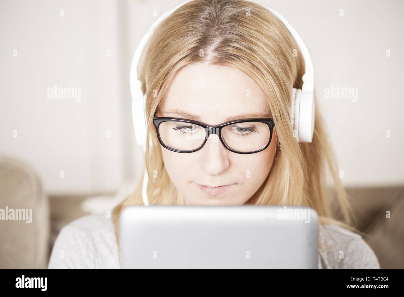 Blond young woman with headphones and tablet PC Stock Photo