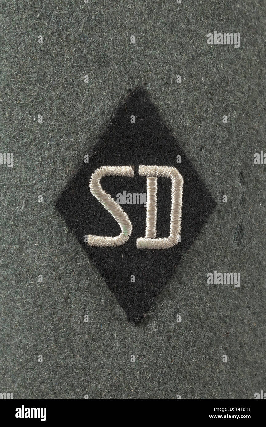 A field tunic M 38 for an SD-Hauptscharführer depot piece from the duty station in Prague Cut in the style of the black tunic, made of field-grey woollen cloth with metal buttons, brown lining with bandage pack pocket and depot stamp 'G.St. Prag'. Black collar patches without piping (from 1942 onwards), slip-on shoulder-boards with police pattern but with black interweaves and middle section. Sleeve eagle and SD sleeve diamond in light-coloured RZM embroidery on black ground. War Merit Cross ribbon, field orders clasp with SS Long Service Award and pinned-on SA Sports Badge, Editorial-Use-Only Stock Photo