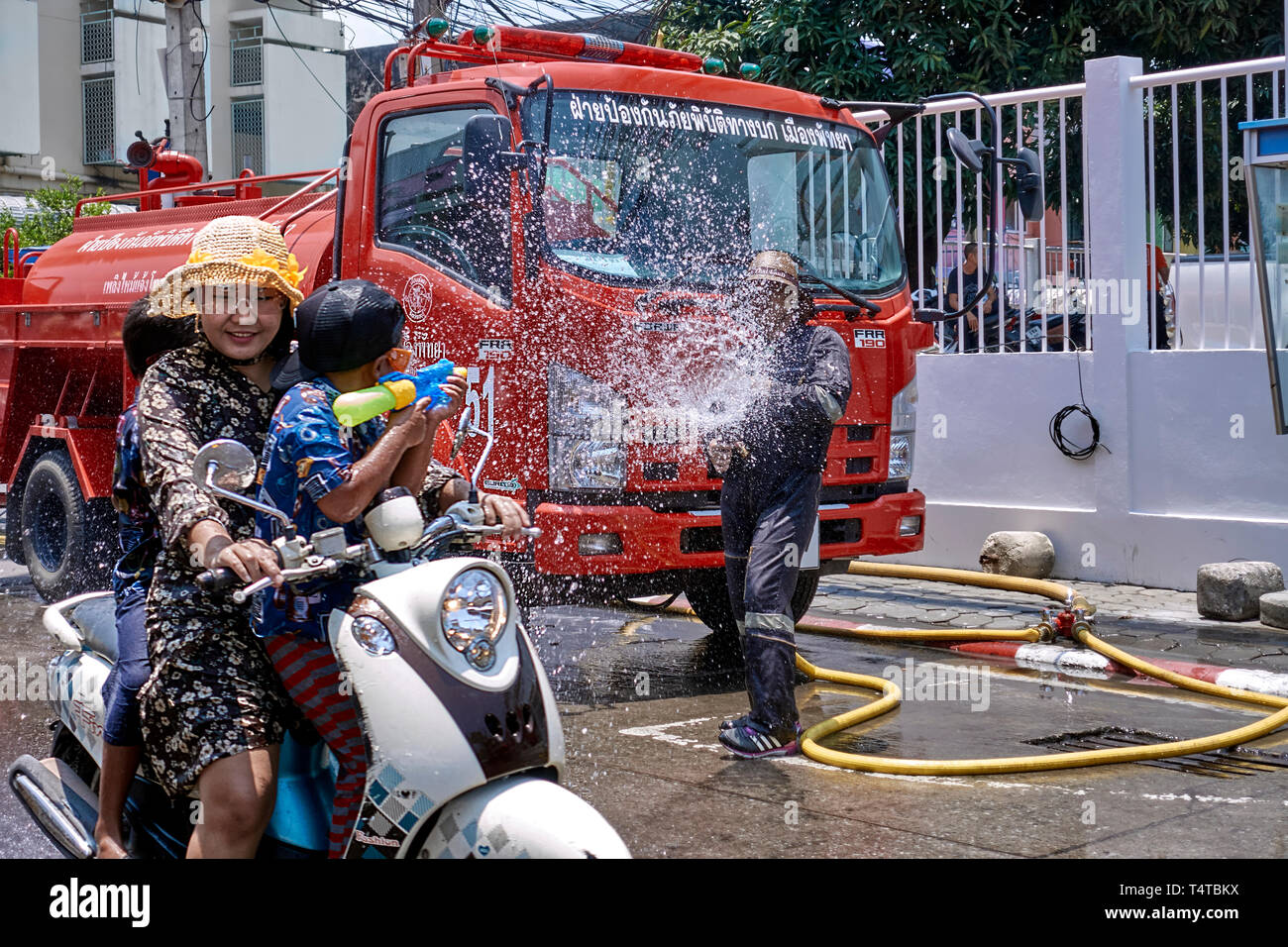 Songkran Thailand New Year and water festival 2019 with a young boy clearly outgunned by the fireman and his fire truck. Stock Photo