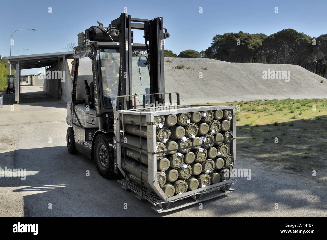 Naval artillery shell detonation casings being transported by forklift. from a concrete bunker, to an RAN frigate. Stock Photo
