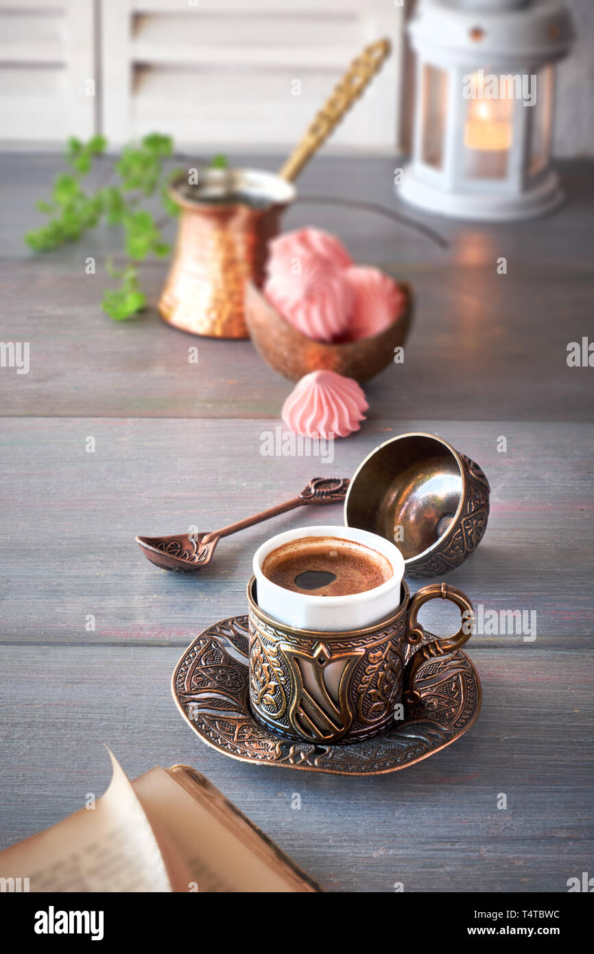 Oriental coffee cooked in traditional Turkish copper coffee pot and  served in a matching cup in ornate metal cup holder Stock Photo