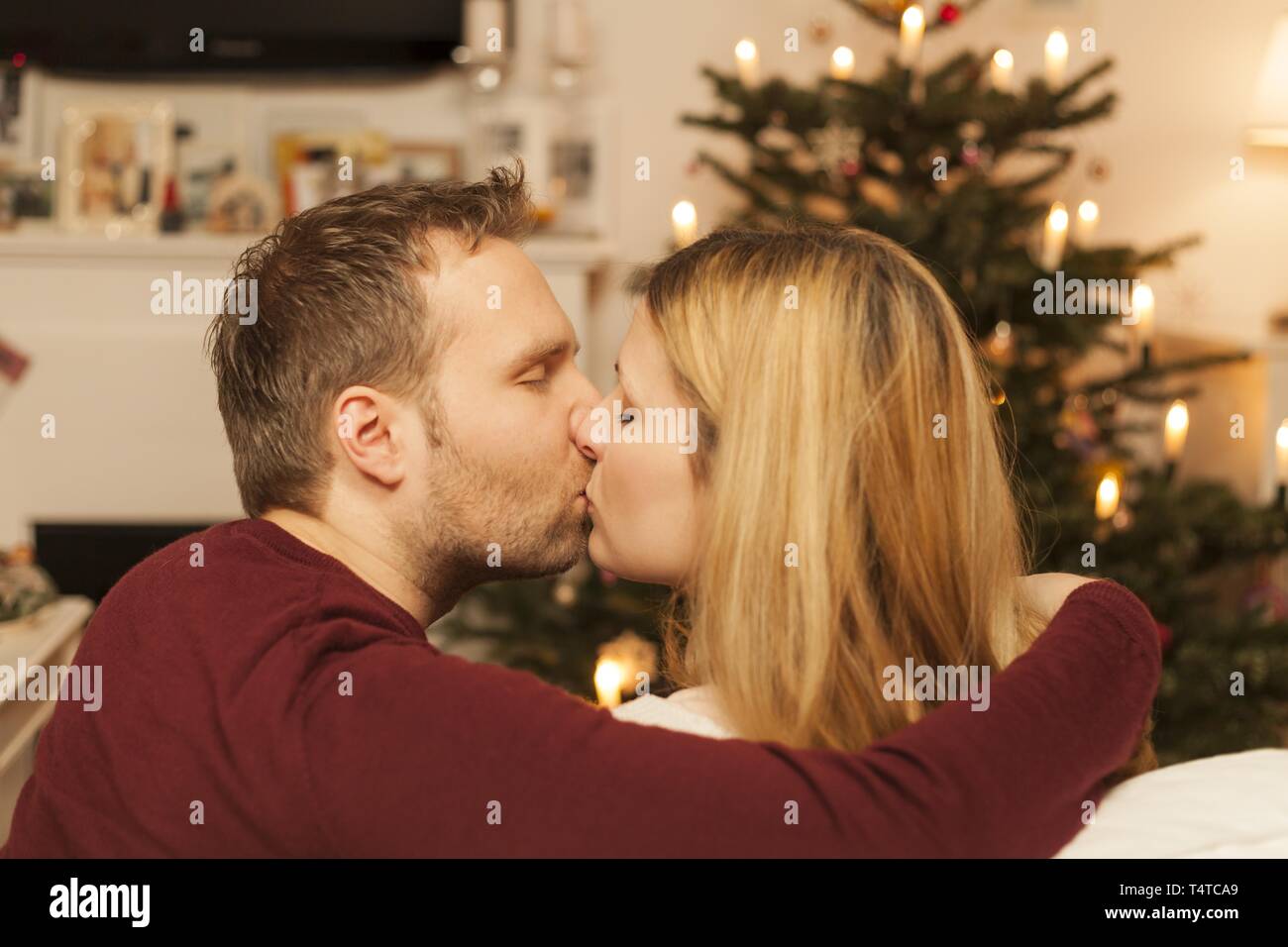 Young couple kissing in front of Christmas tree, Germany, Europe Stock Photo