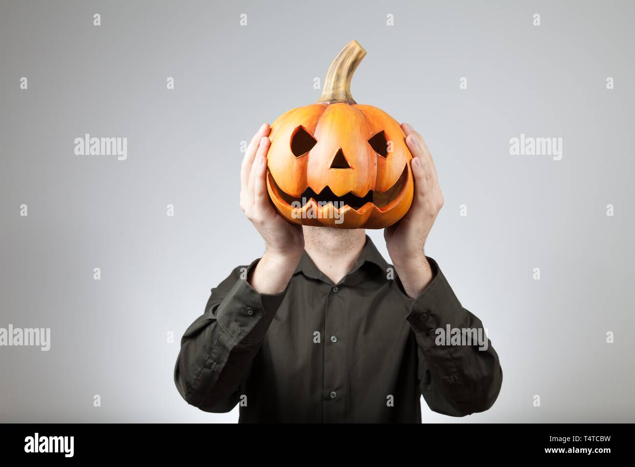 Man holding a clay pumpkin in front of his head Stock Photo