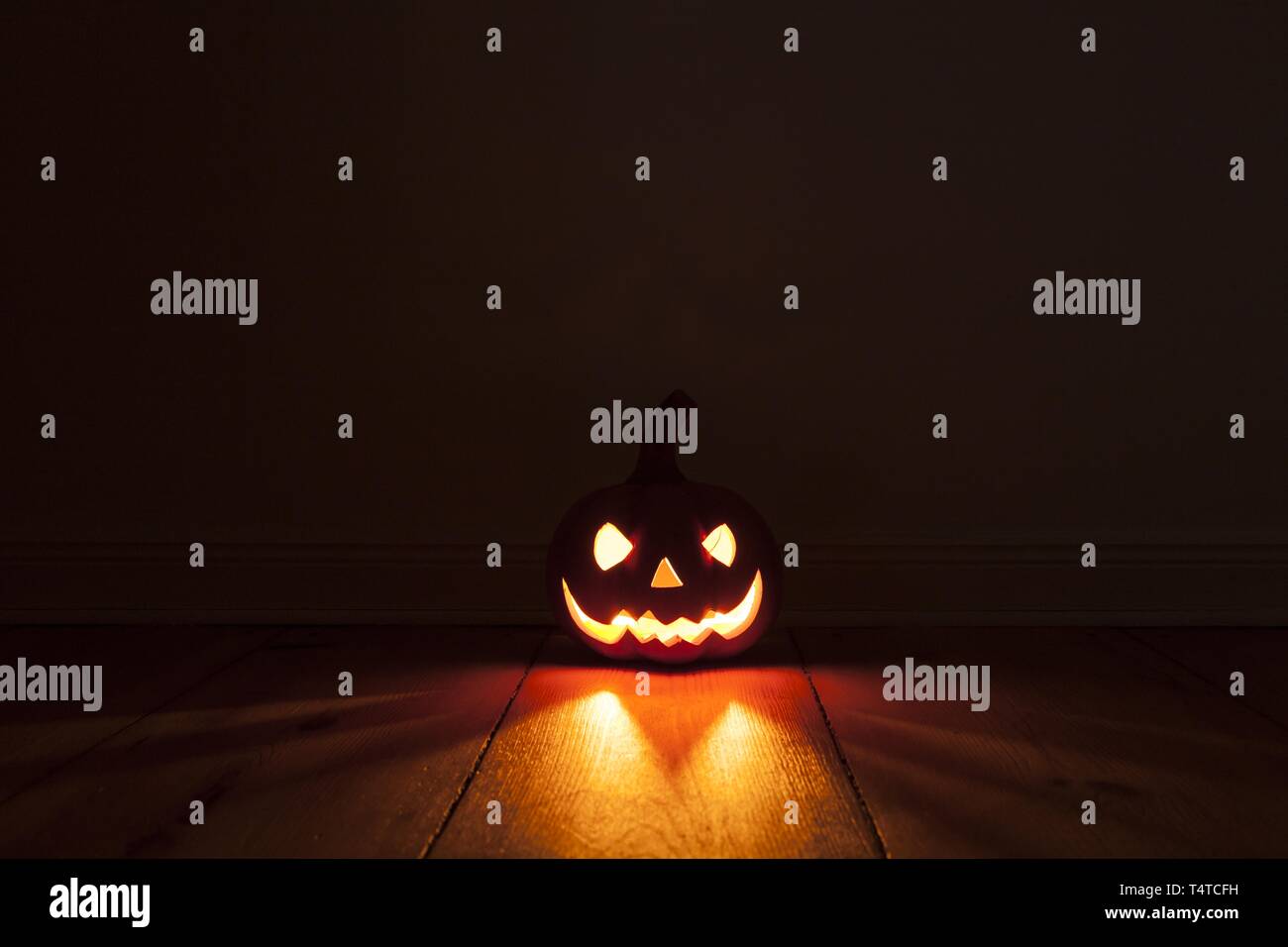 Grinning, luminous tone pumpkin on wooden floor, Halloween Stock Photo