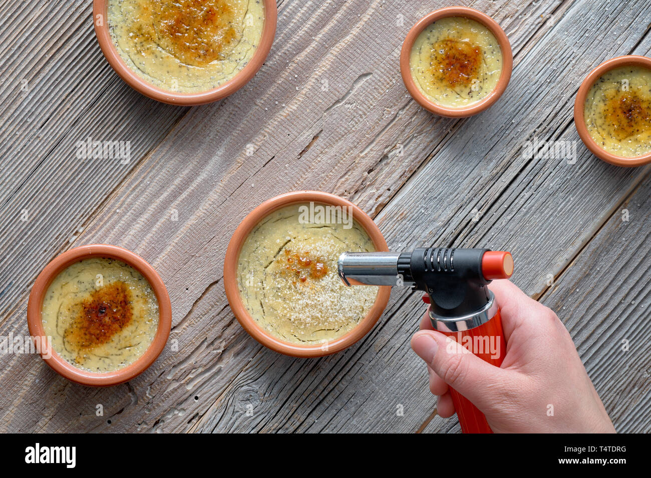 Making creme brulee. Flat lay on rustic wooden table with ceramic brown