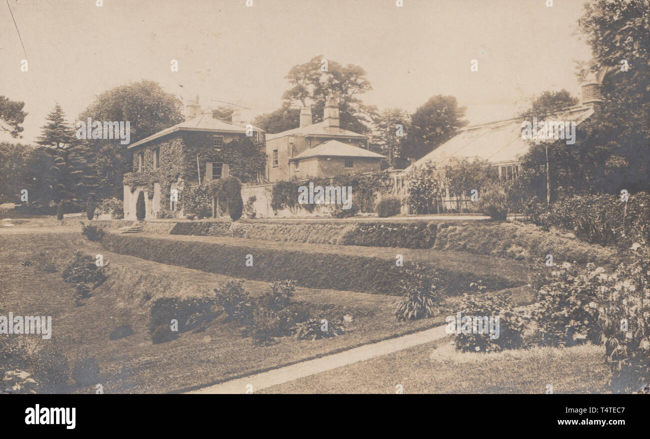 Vintage Photographic Postcard Showing an Historic British Detached House With Landscaped Grounds. Stock Photo