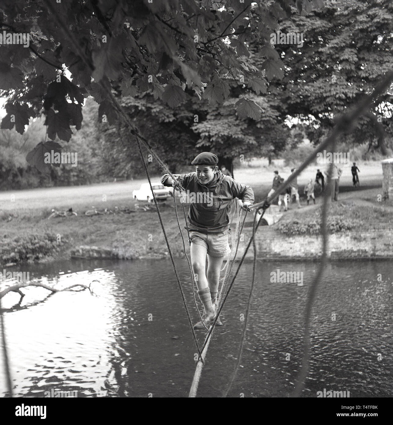 1960s, historical, a young adventure scout crosses a river on a rope