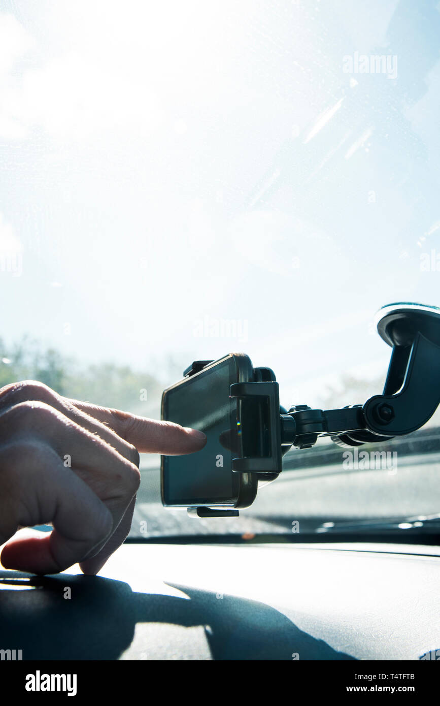 closeup of a young caucasian man using a smartphone as a GPS mounted in a holder stuck in the windscreen of a car Stock Photo