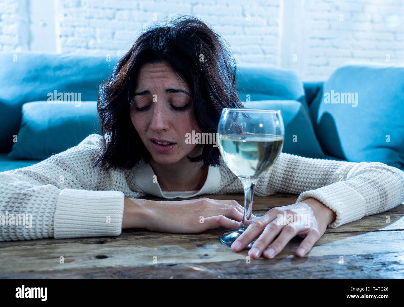 Stressed and hopeless young woman drinking a glass of wine alone at