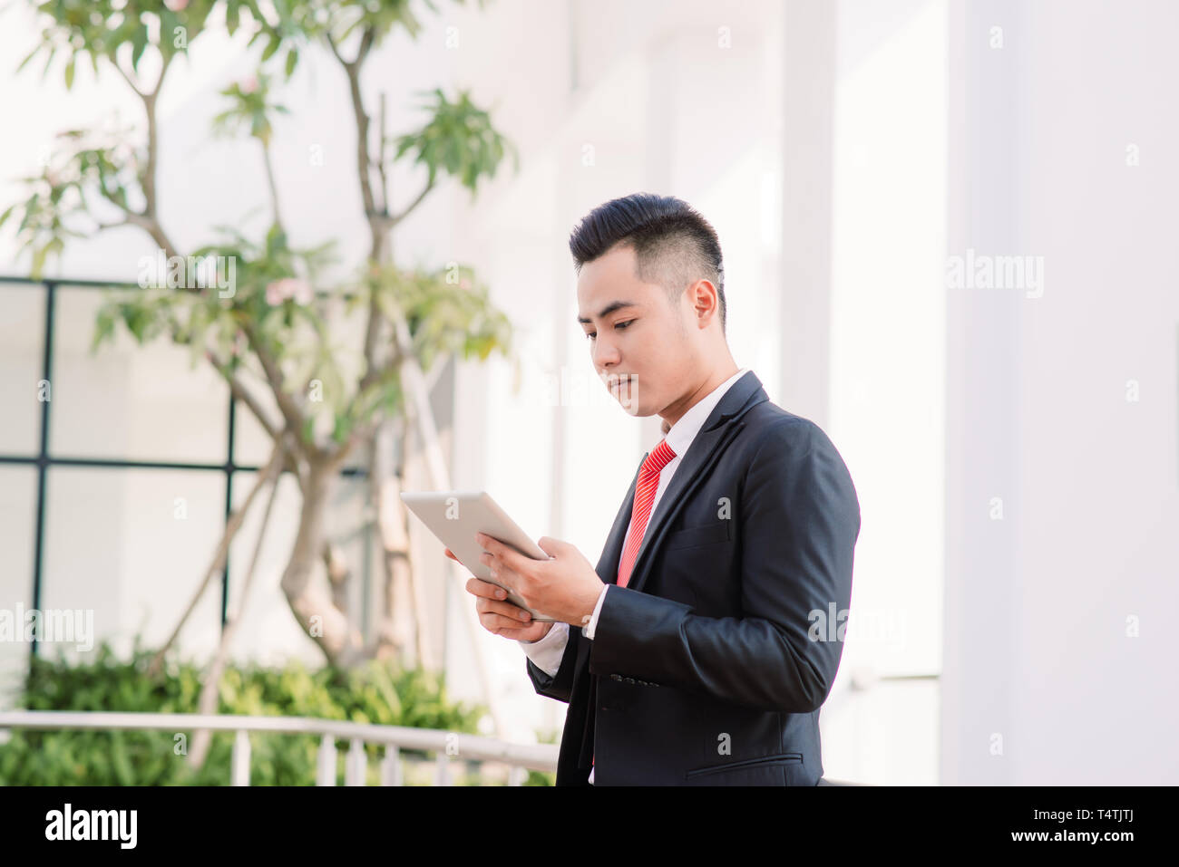 Young Asian Businessman working on tablet, Lifestyle of modern male to communicate, message or use technology in business, Always connected concept, F Stock Photo