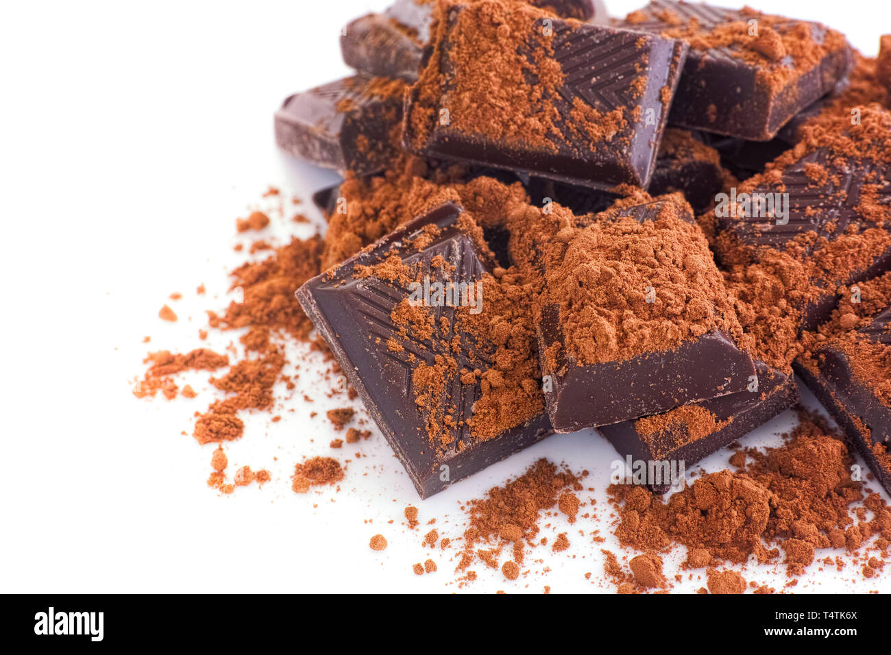 Broken dark chocolate with cocoa powder. White background Stock Photo