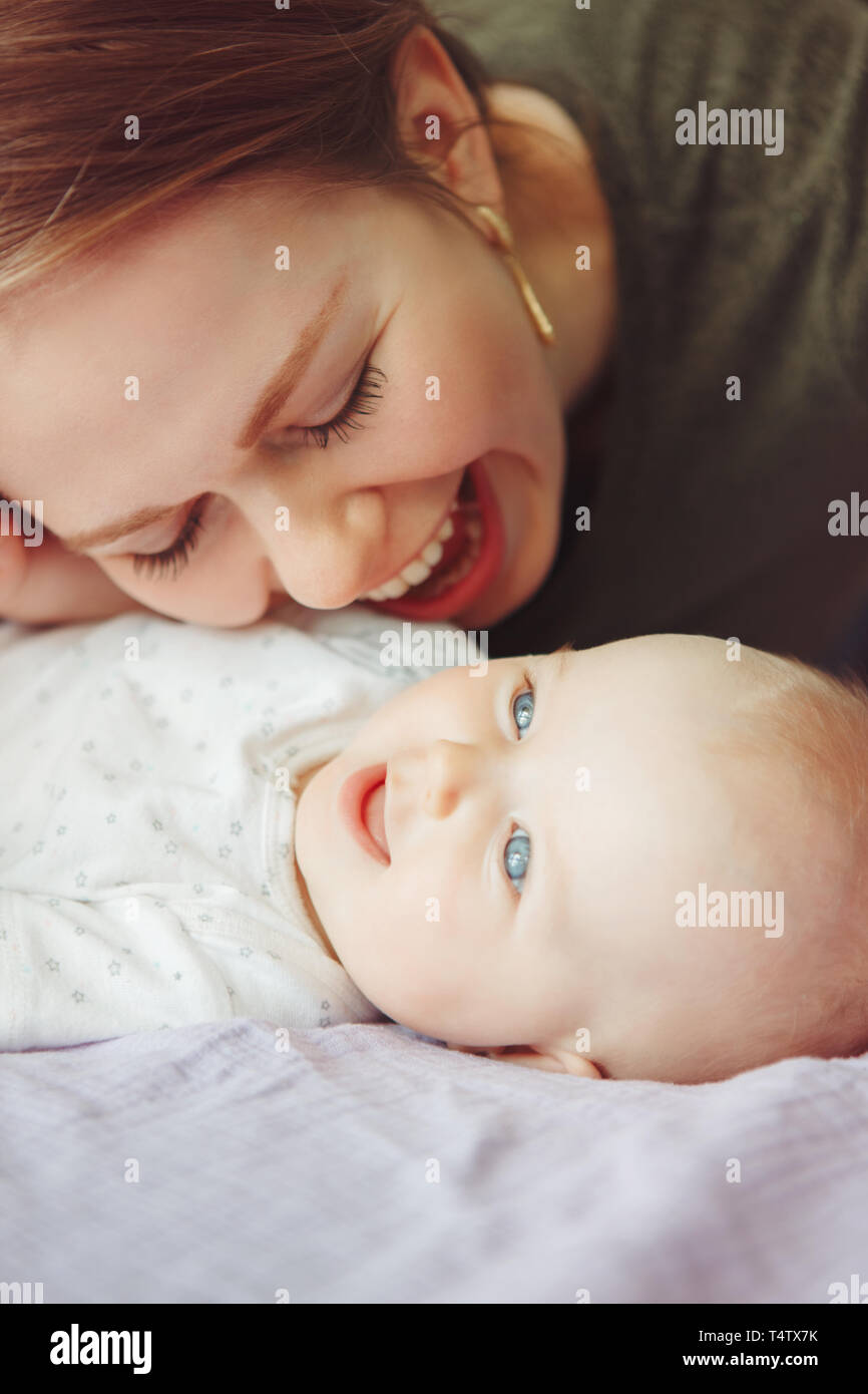 Closeup of young Caucasian woman mother hugging kissing playing with ...