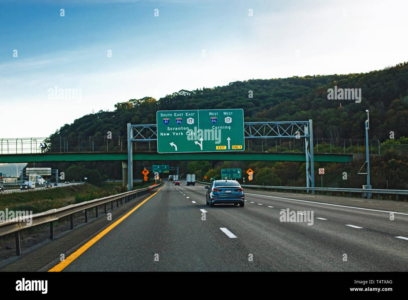 Cars on highway freeway at evening sunset in american city country. Road to New York with street signs and land surface transport vehicles. Travel and Stock Photo