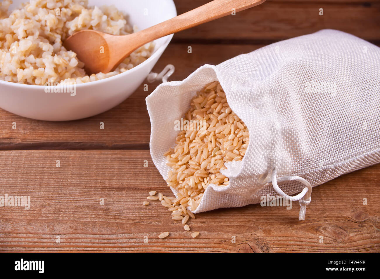 Dry Cooked Rice Dry rice and cooked brown rice in white bowl with on the old wooden ...