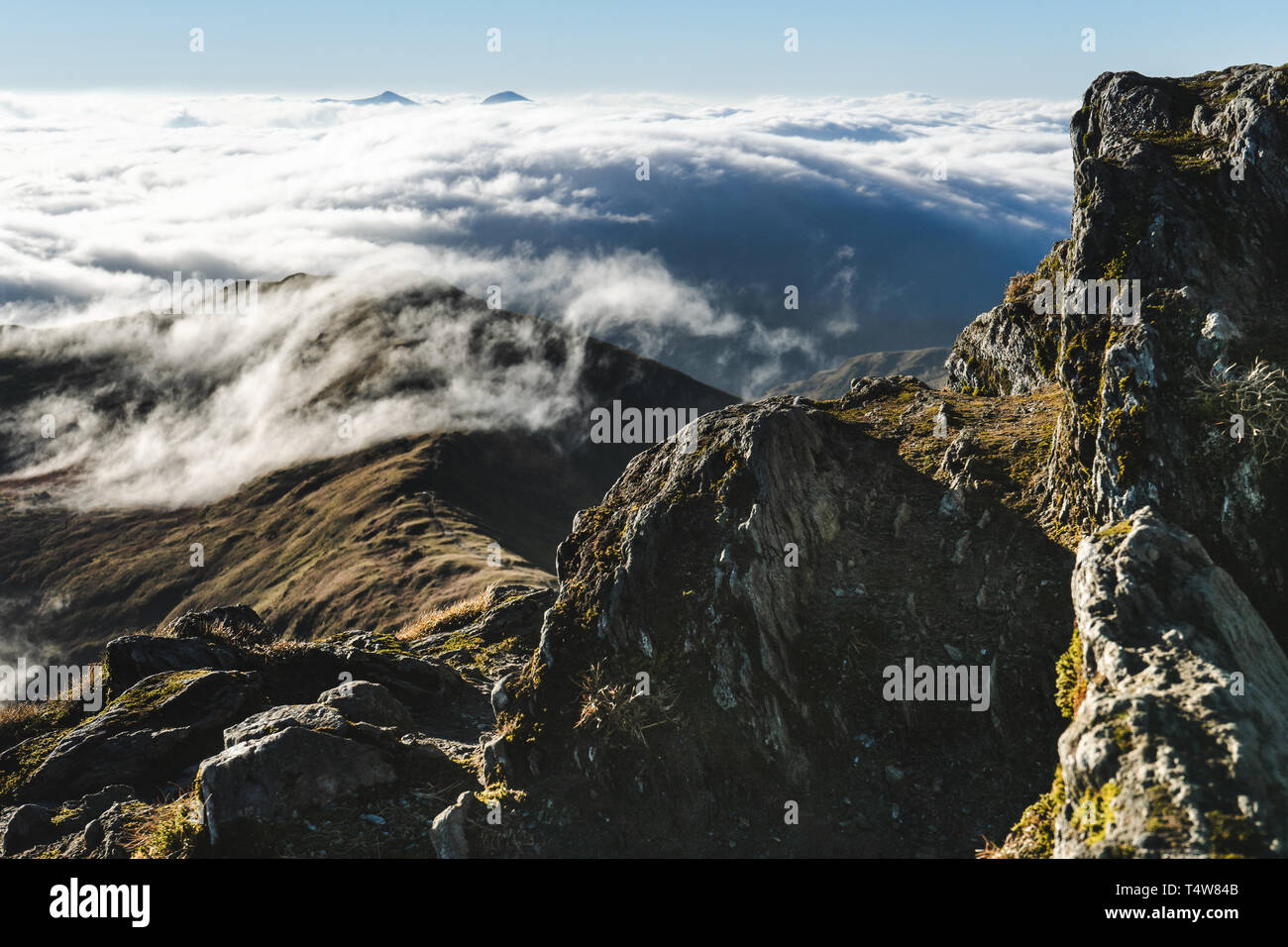 Sea of clouds below summits of mountains Stock Photo