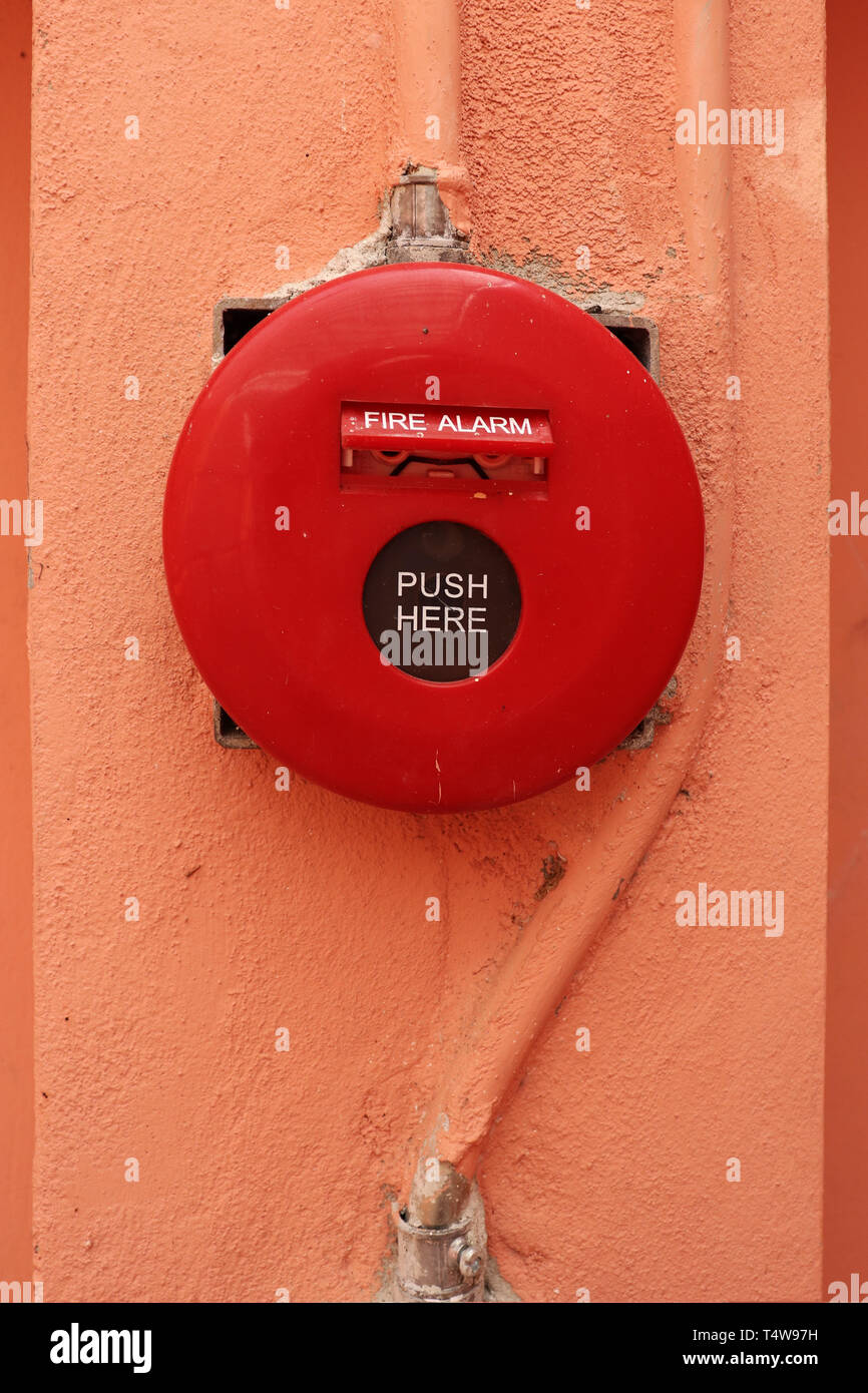 Red fire alarm on orange wall. Stock Photo