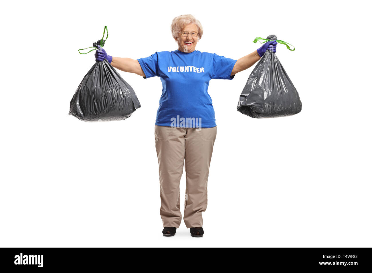 Full length portrait of an elderly woman volunteer posing with two waste bags isolated on white background Stock Photo