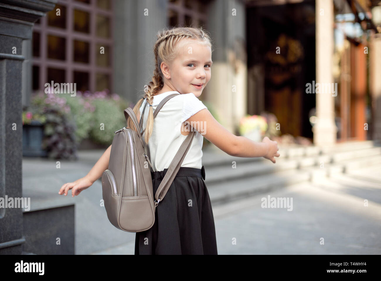 Happy smiling girl is going to school for the first time with bag go to elementary school. Pupil go study with backpack. Stock Photo