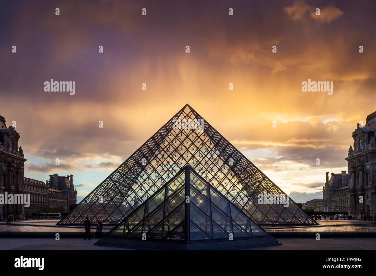 Clearing rainstorm over the iconic glass pyramid in the courtyard of Musee du Louvre, Paris, France Stock Photo