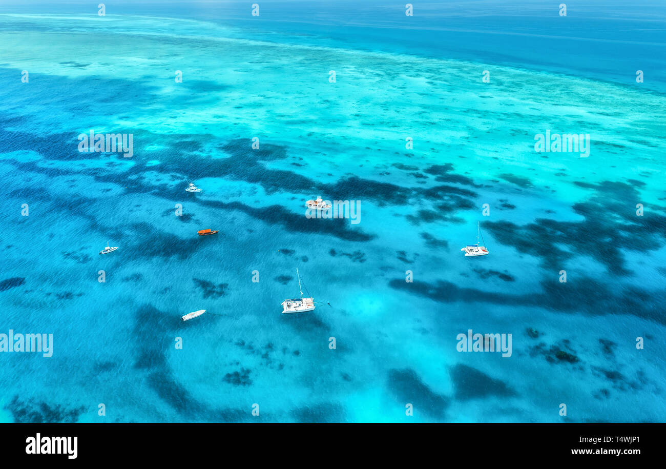 Aerial view of luxury yachts and fishing boats in clear blue sea at ...