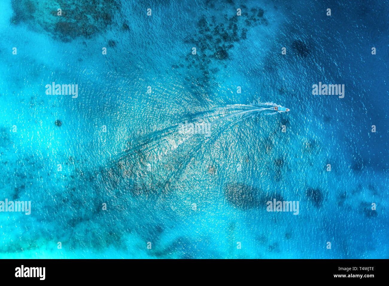 Aerial view of the fishing boat in clear blue water at sunset in summer ...