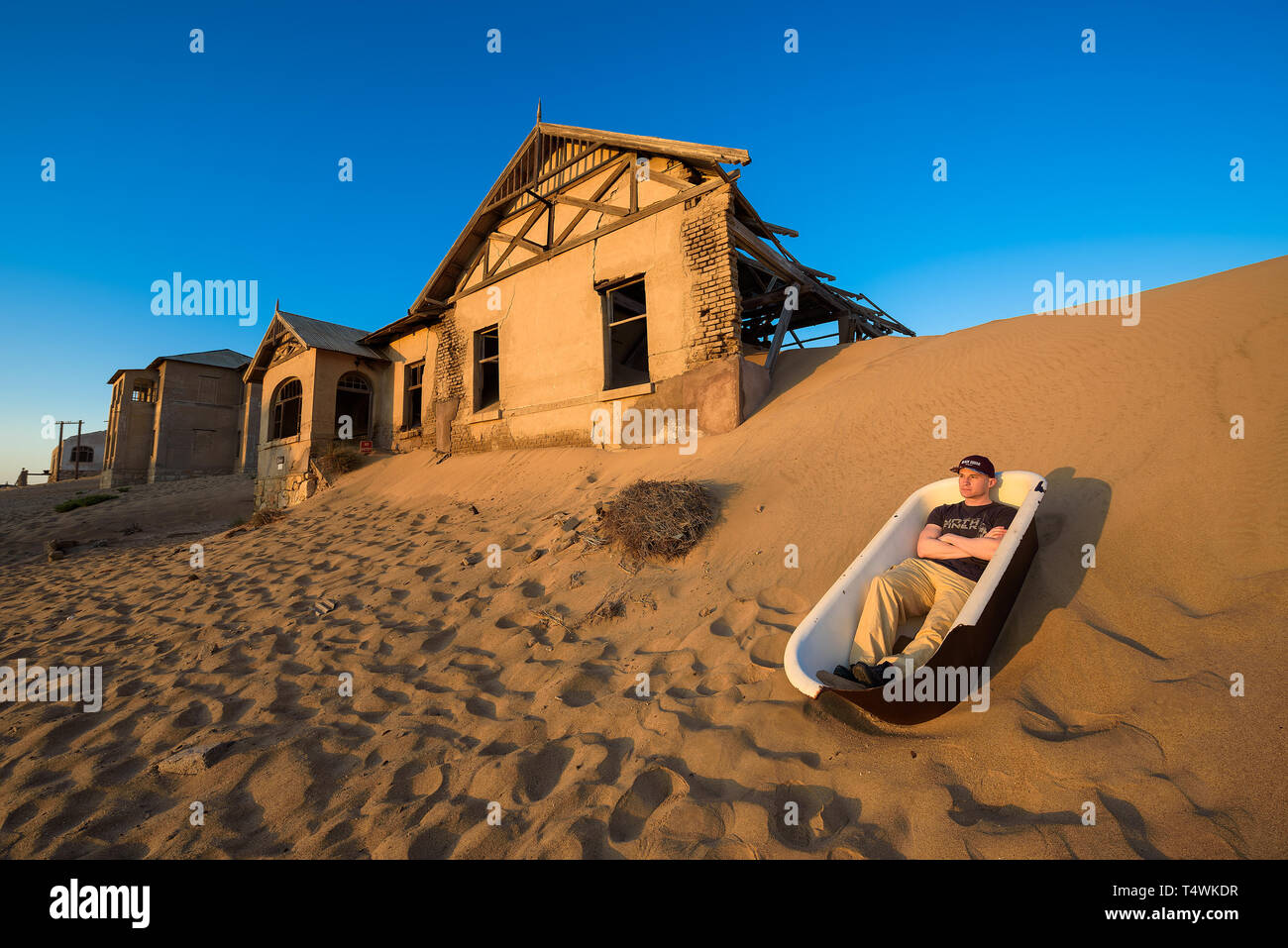 Tourist sits in a bathtub in Kolmanskop ghost town, Namibia Stock Photo