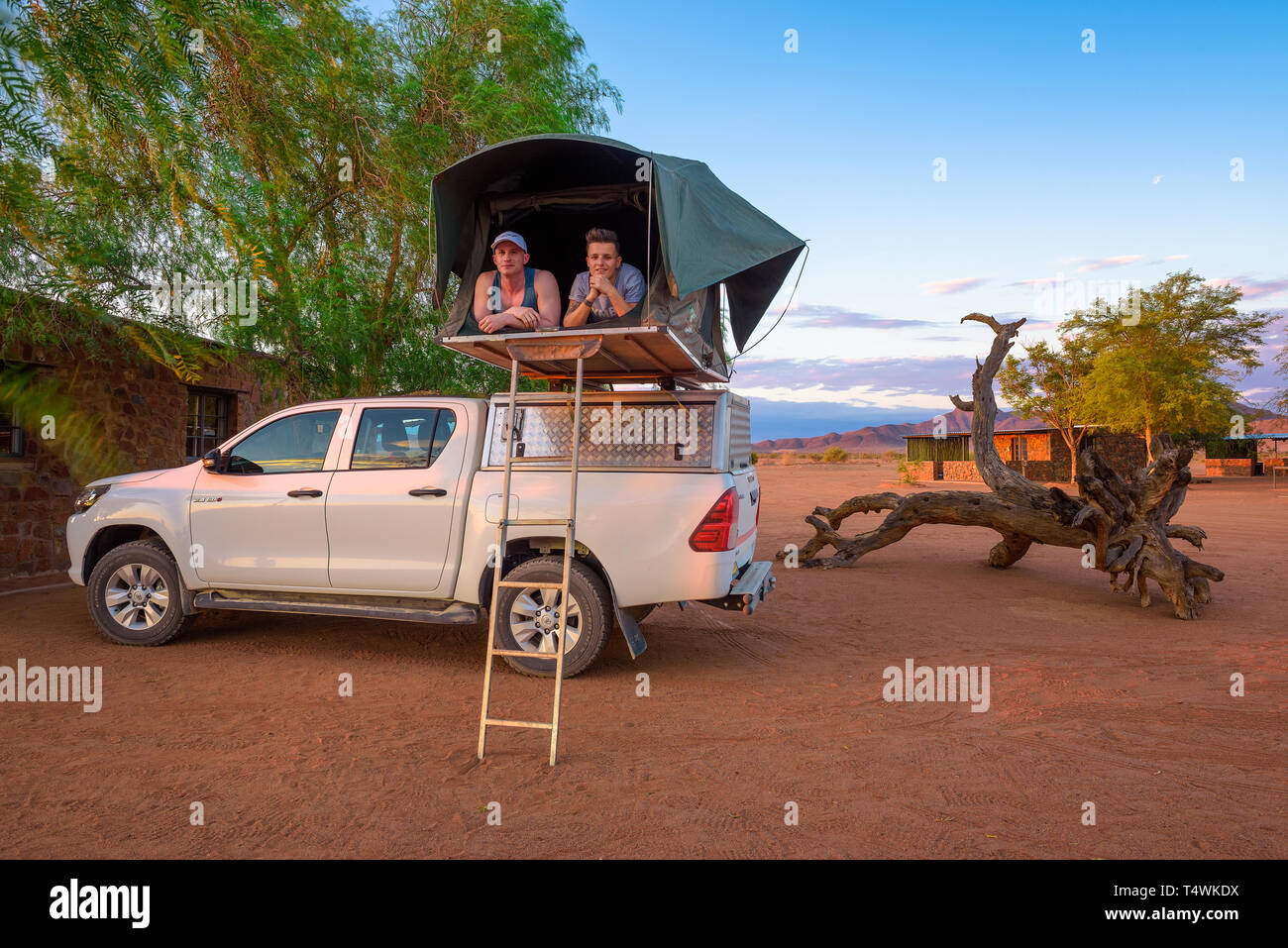 Young couple lying in a tent located on the roof of a pickup 4x4 car Stock Photo