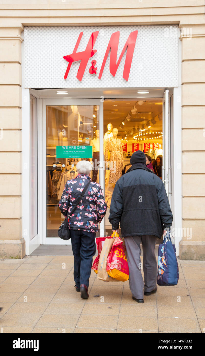 Shoppers walking into the high street  fashion clothes  shop retailer H & M the town of Cheltenham Gloucestershire England UK Stock Photo