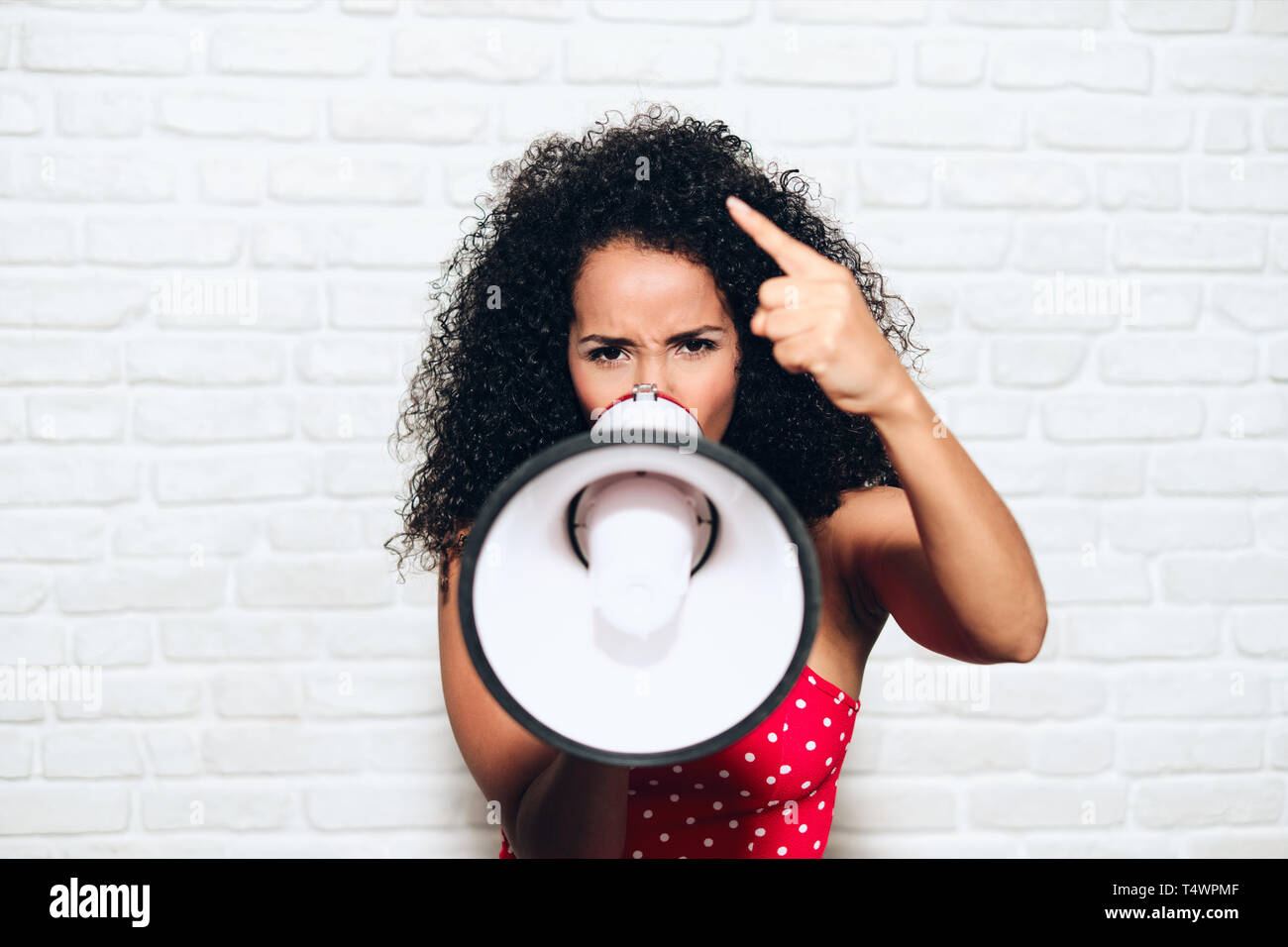 Portrait of angry african american woman shouting with megaphone for protest. Black girl showing rage, anger and rebellion for human rights, strike, p Stock Photo