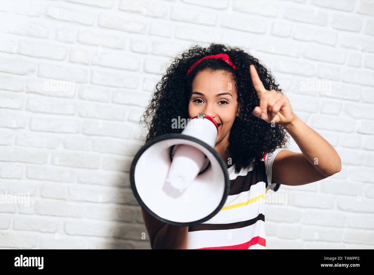 Portrait of happy african american woman shouting with megaphone for promotion, advertising. Black girl smiling and laughing for fun, joy, happiness Stock Photo