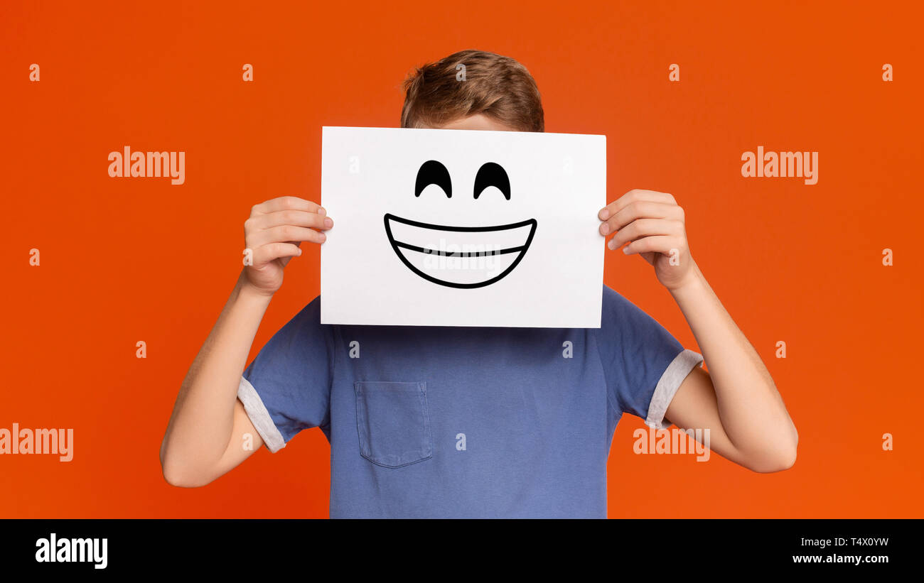 Teenage boy holding paper with smiley face Stock Photo