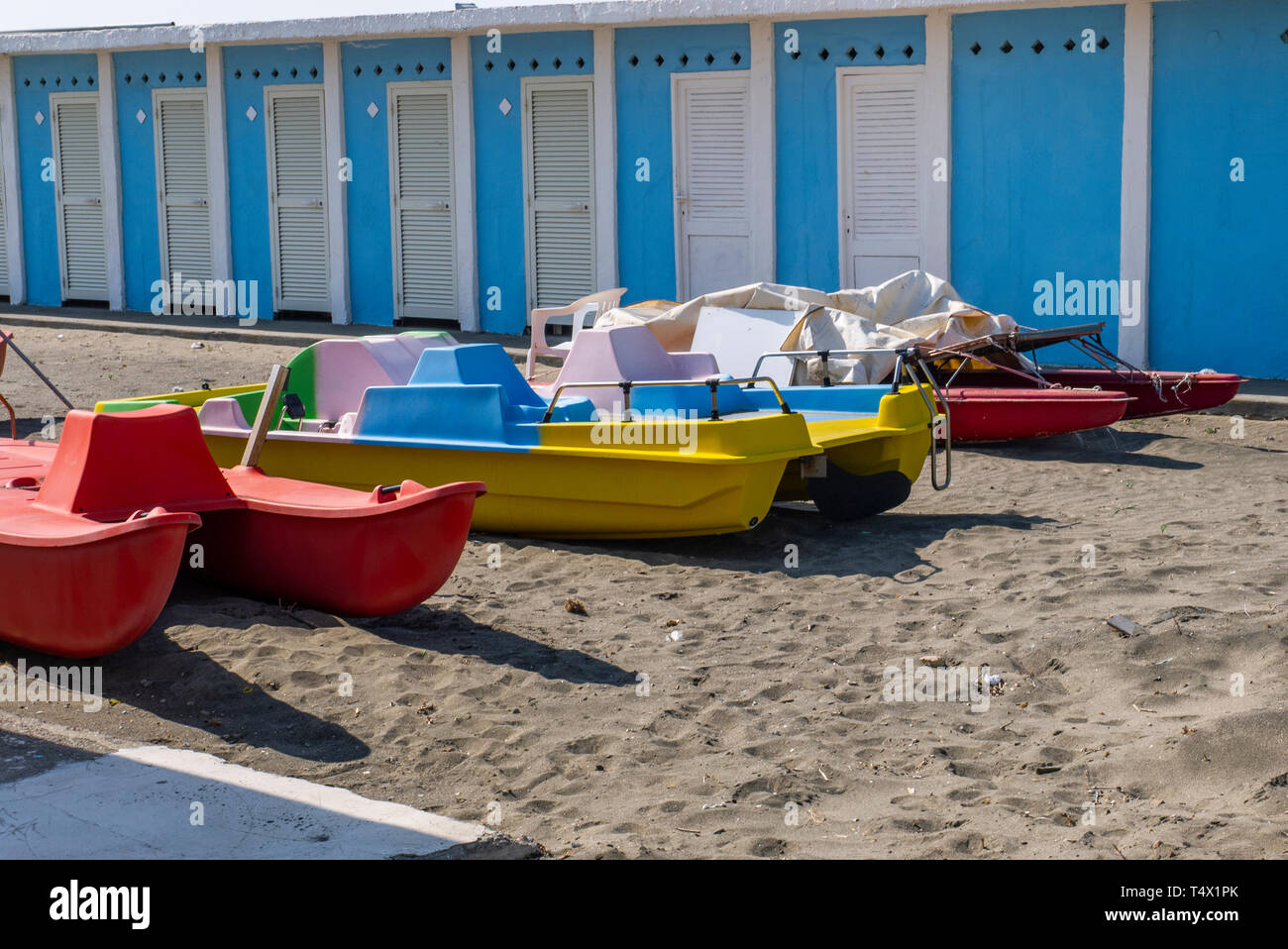 colorful boats on the sandy beach of a beach establishment, with white cabins in the background Stock Photo