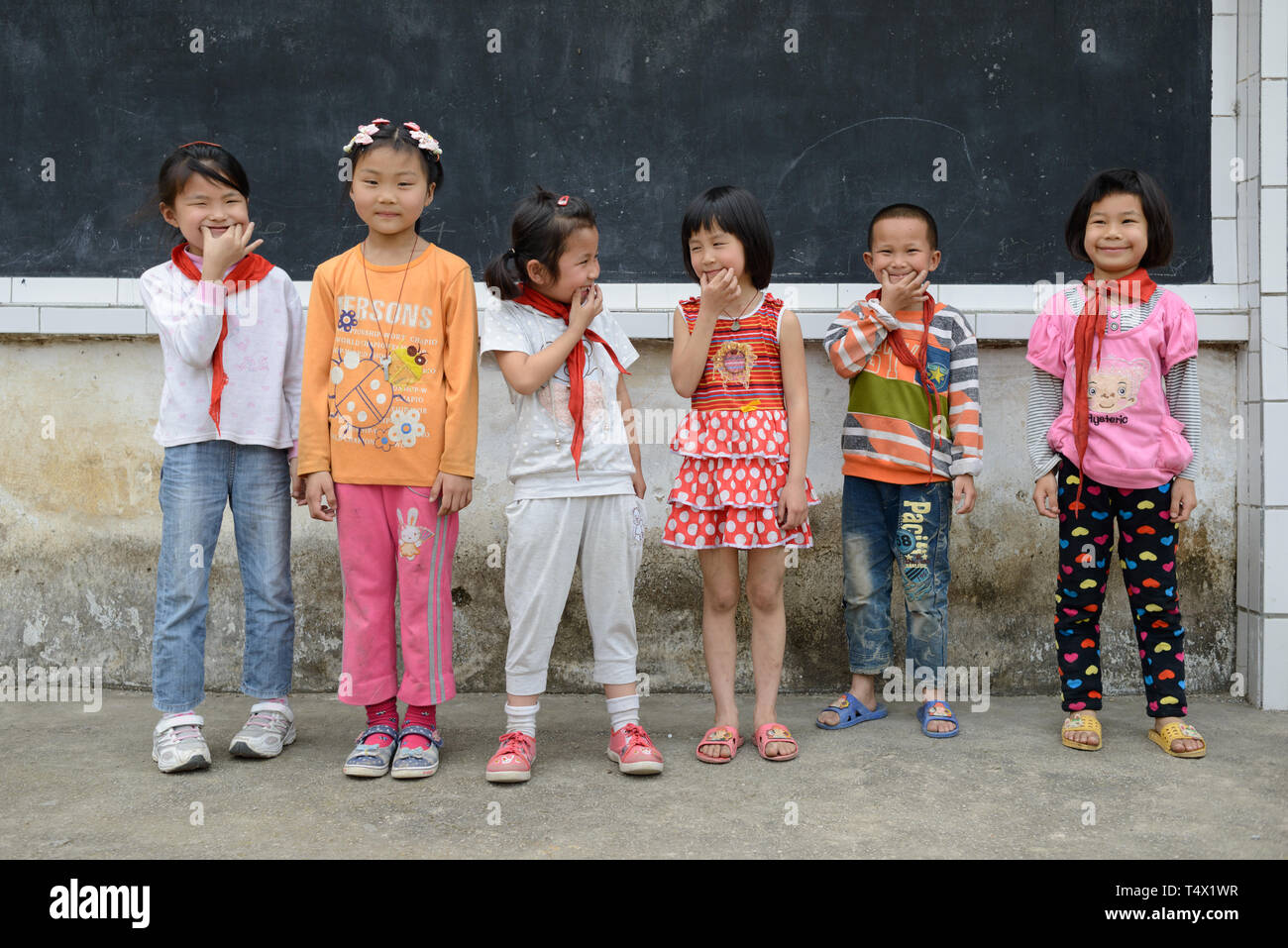 Primary age school children line up for a photo, laughing and playing, in the school playground in rural Guangxi region, central southern China. Stock Photo