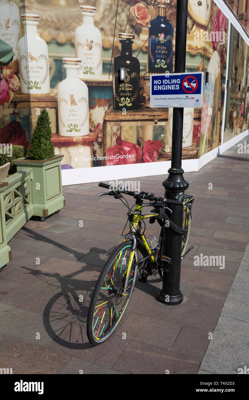 A No Idling Engines sign aimed at waiting black cab drivers, and a locked-up bike at the rear of the Harrods Department Store in Knightsbridge, on 15th April 2019, in London, England. Stock Photo