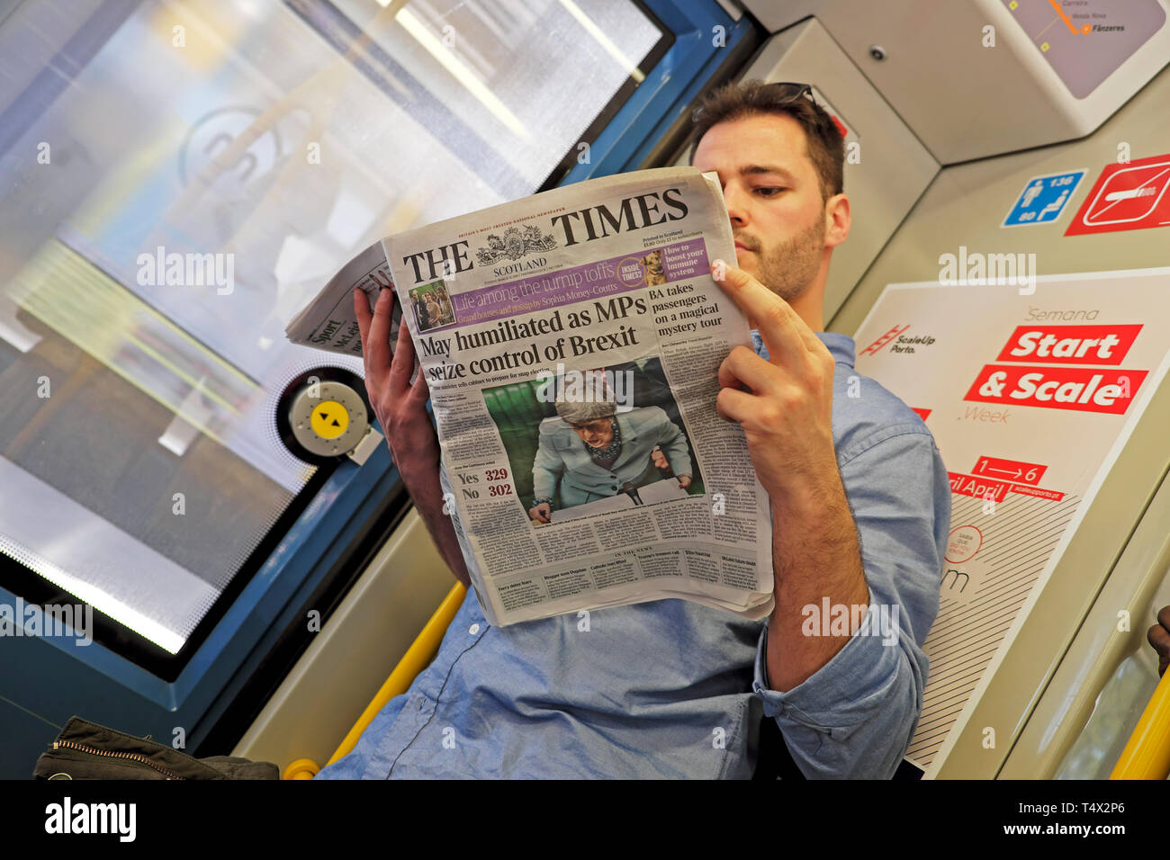Man reading on train in Europe 'May humiliated as MPs seize control of Brexit' The Times newspaper headline 26 March 2019 Porto Portugal KATHY DEWITT Stock Photo