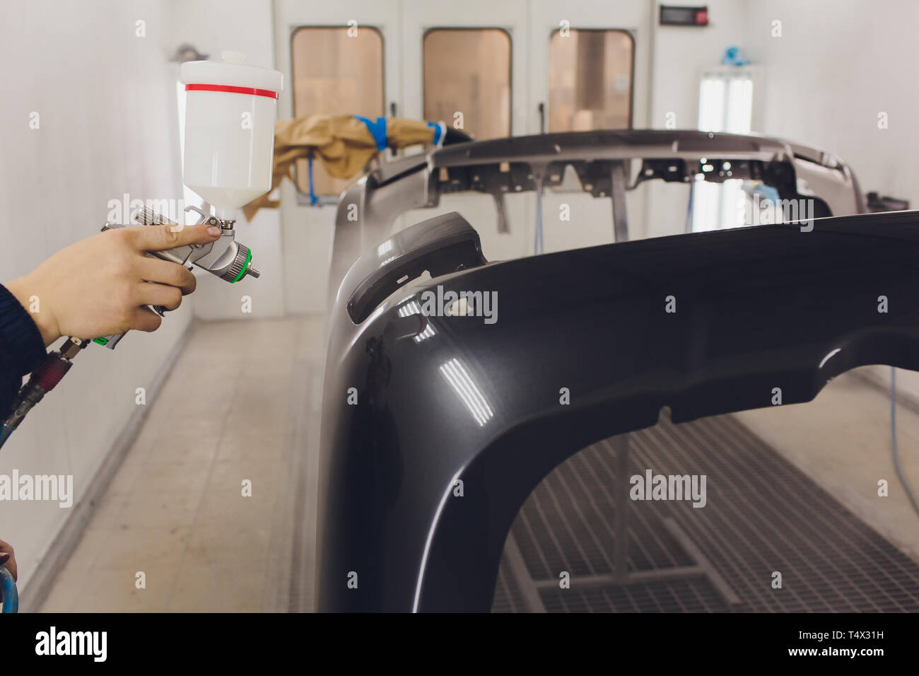 worker painting a car black blank parts in special garage, wearing